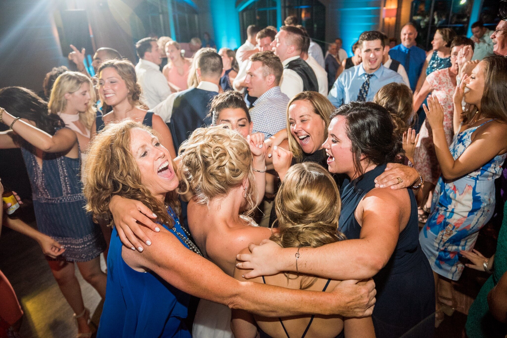 A bride dancing with family and friends on a packed wedding dance floor