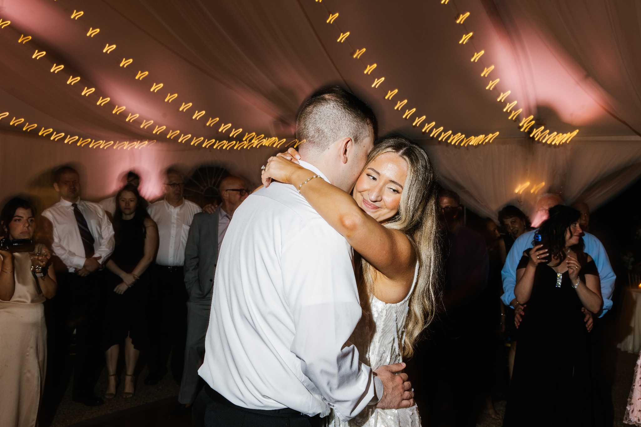 A newlywed couple sharing a dance beneath warm reception lights