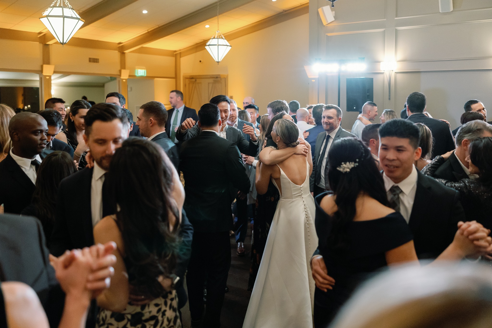 A bride and her guests on a packed dance floor illuminated by elevated wash lighting