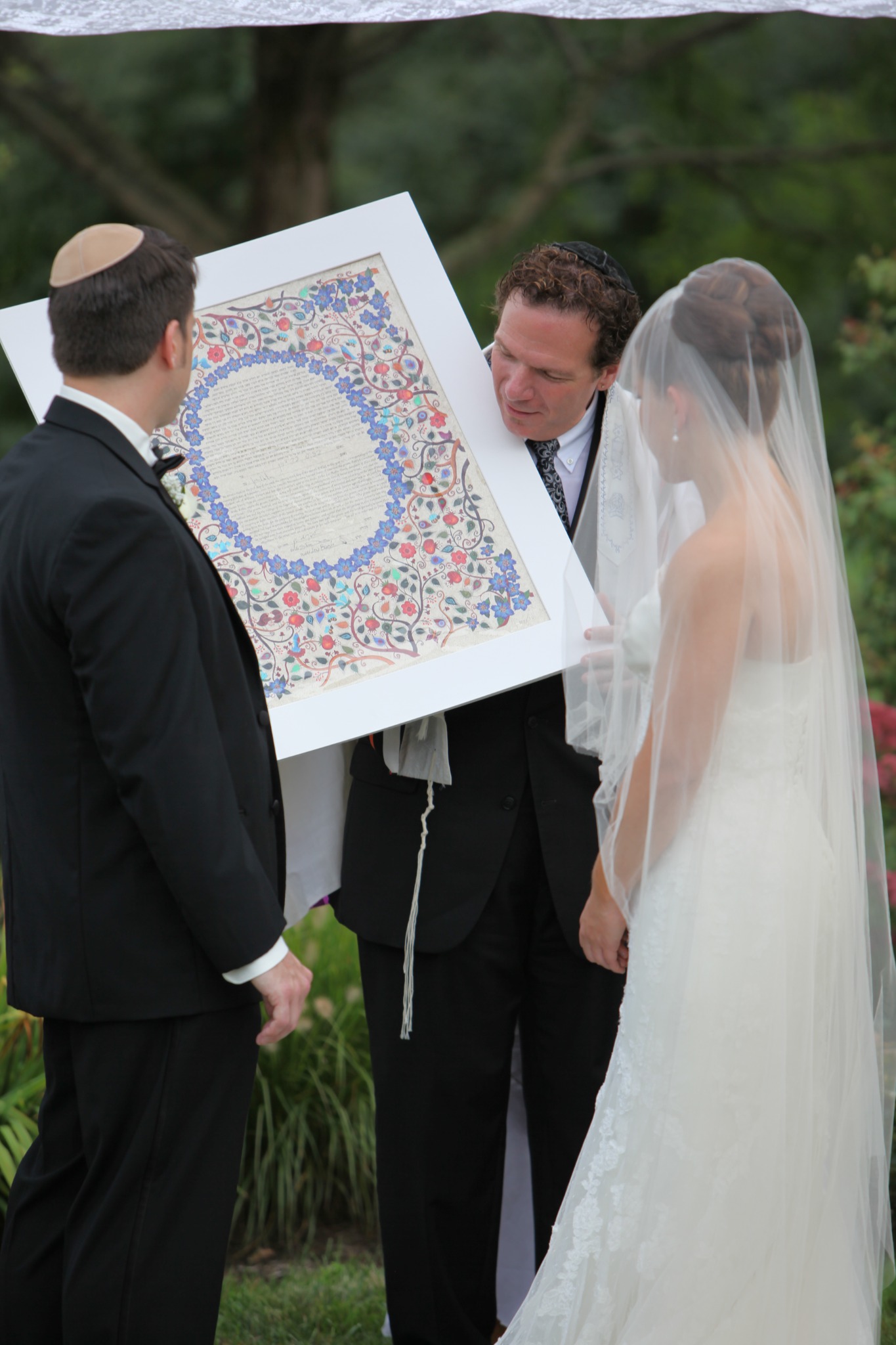 A couple and their officiant viewing their ketubah during a Jewish wedding ceremony