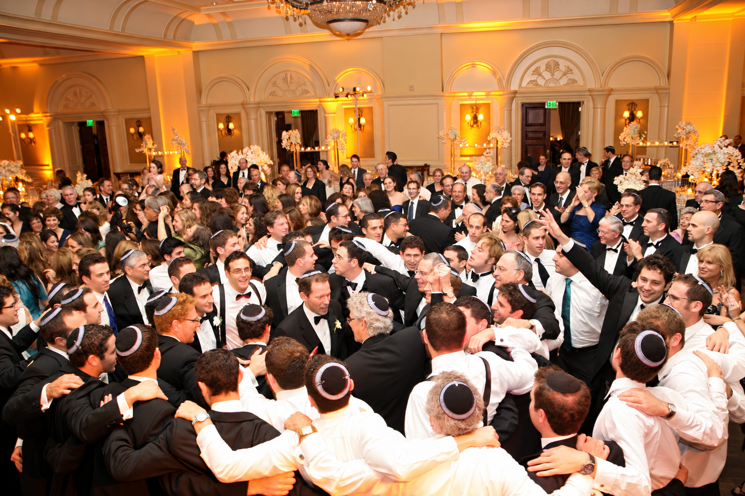 A packed ballroom of wedding guests celebrating together during a Jewish wedding