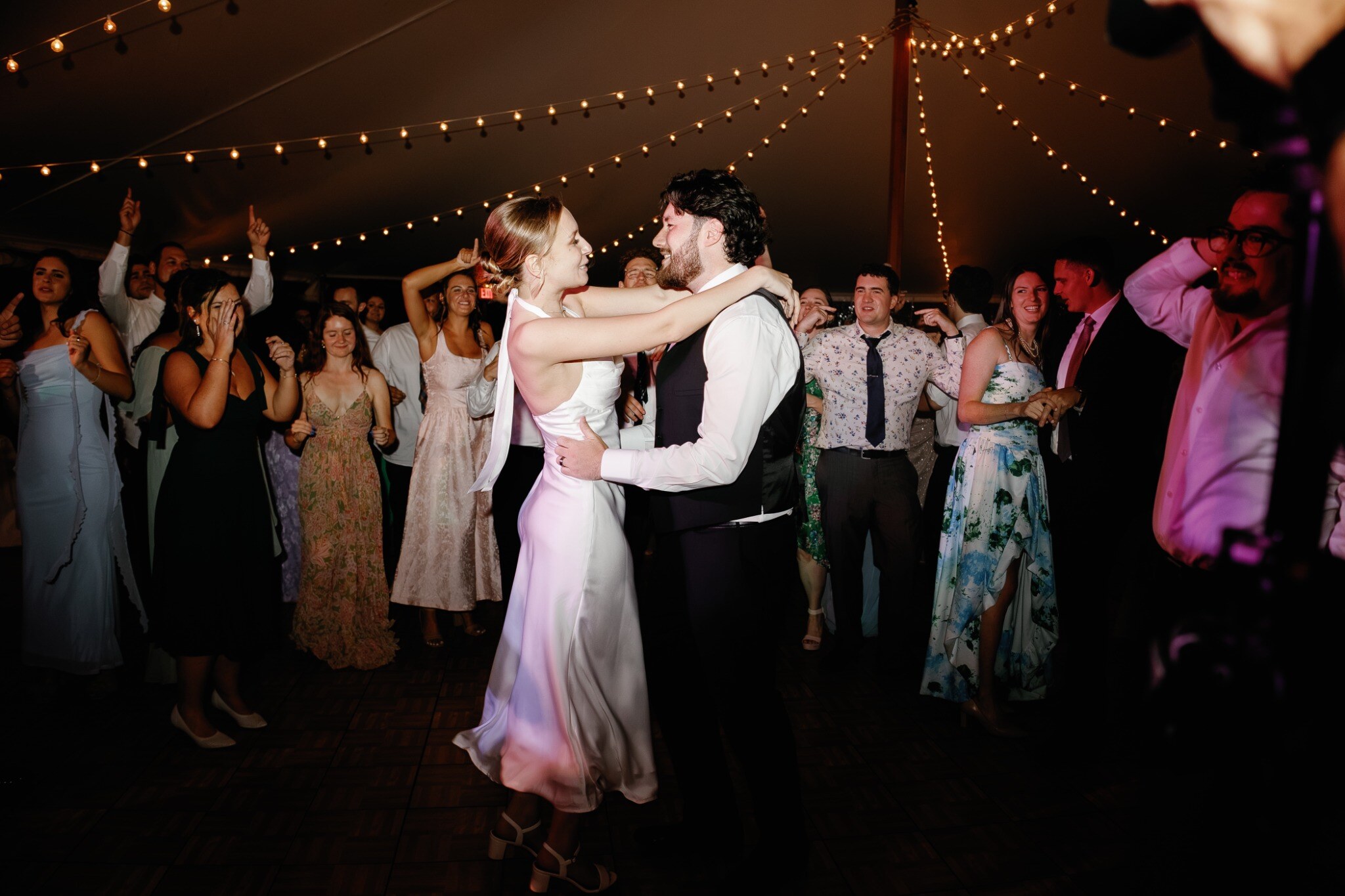 Newlyweds dancing together beneath string lights at a North Shore wedding reception
