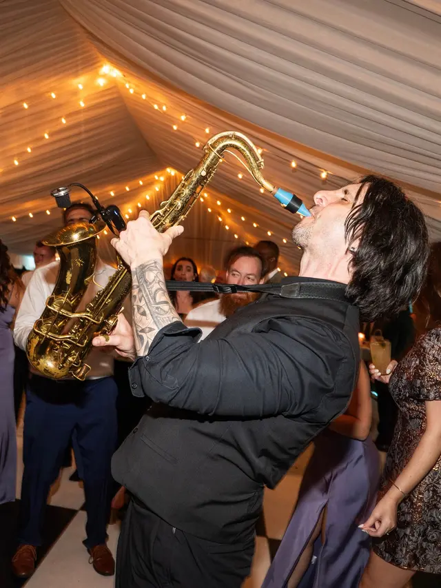 A live saxophone musician performing in the middle of a packed wedding dance floor