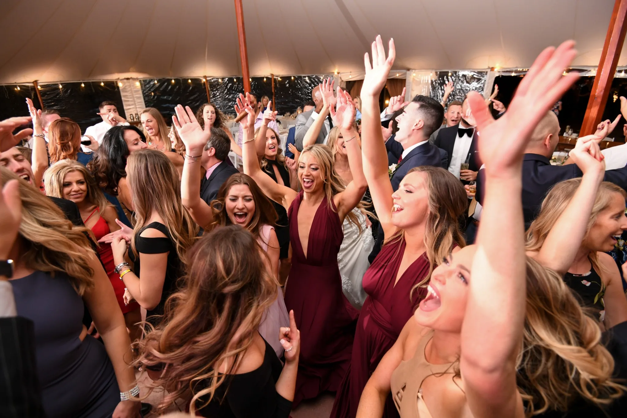 Wedding guests celebrating with their hands raised on a packed dance floor