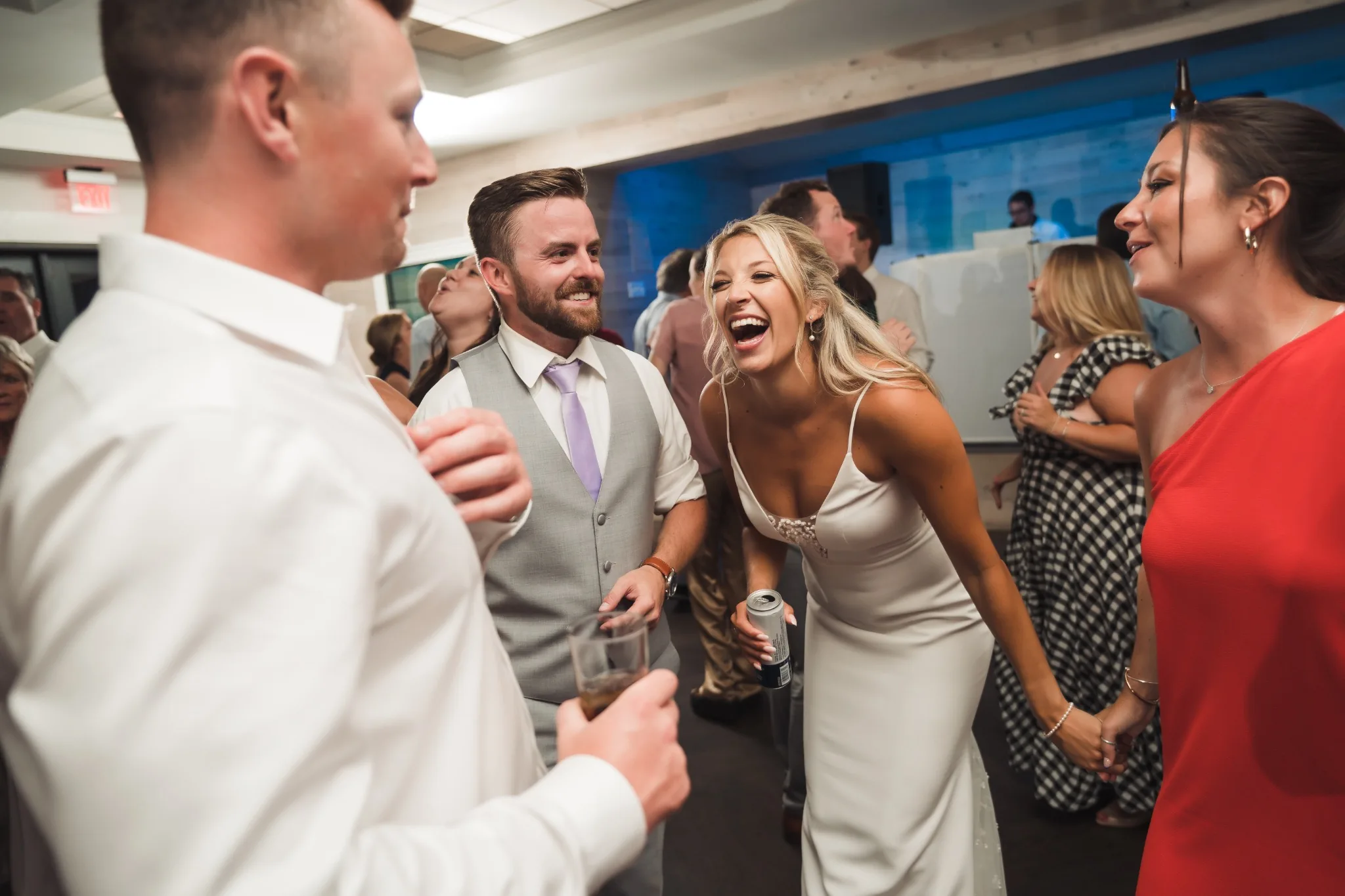A bride and groom laughing and dancing with their wedding guests