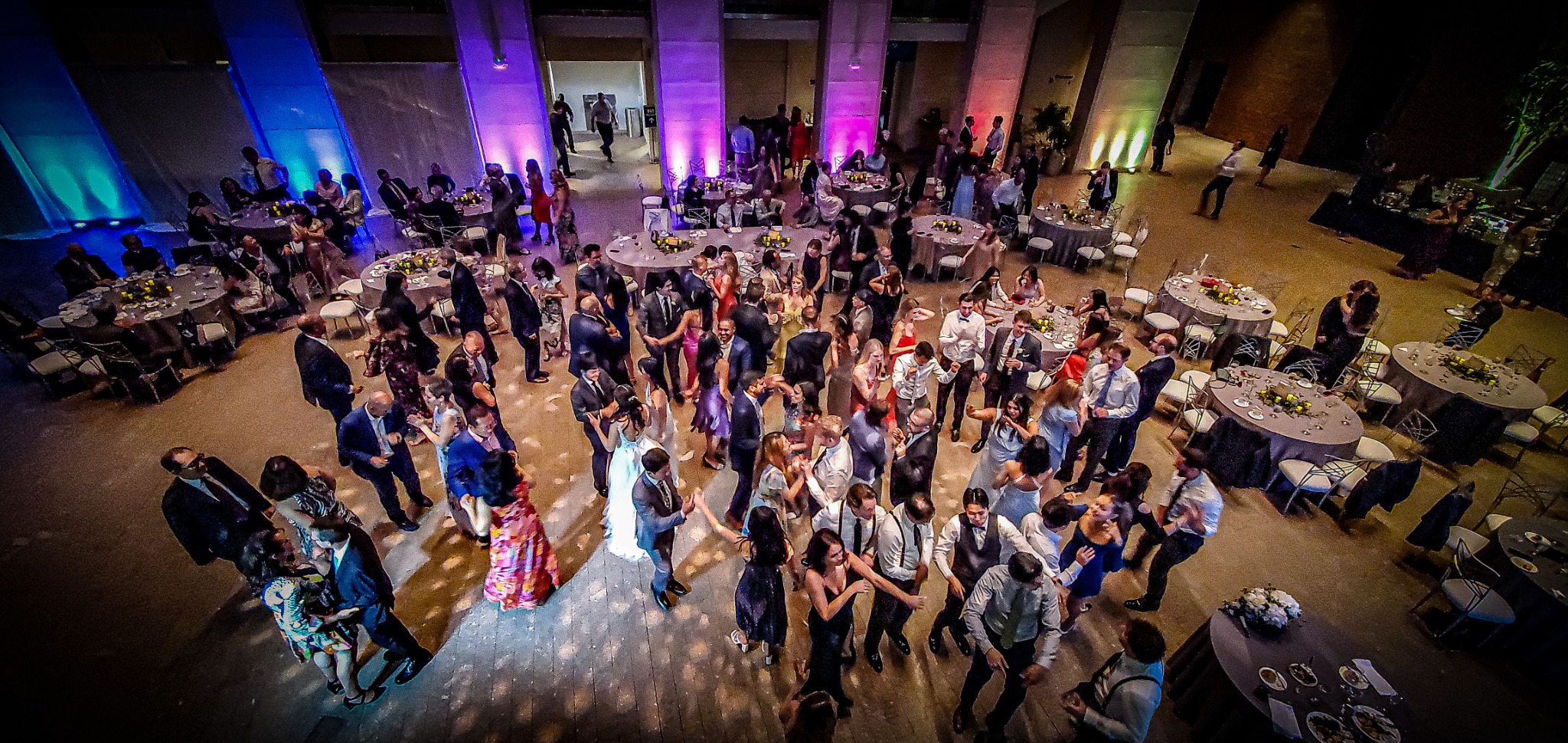 An overhead view of wedding guests filling a colorful reception and dance floor